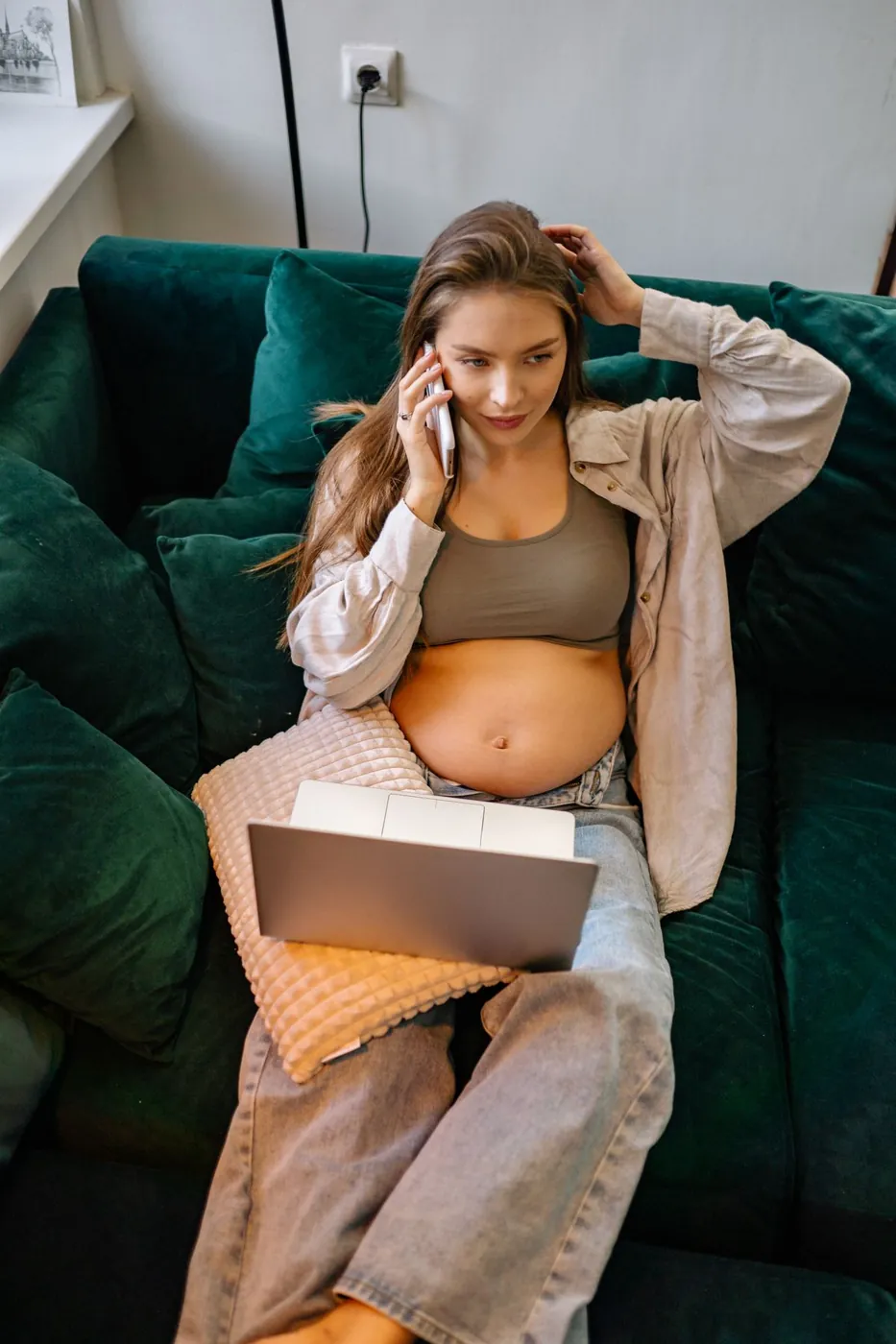 Pregnant woman on the sofa looking worried while on her phone